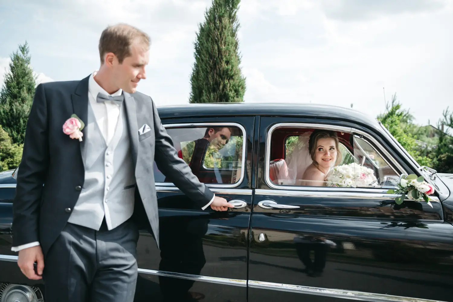 bridegroom-is-standing-by-car-while-bride-is-car